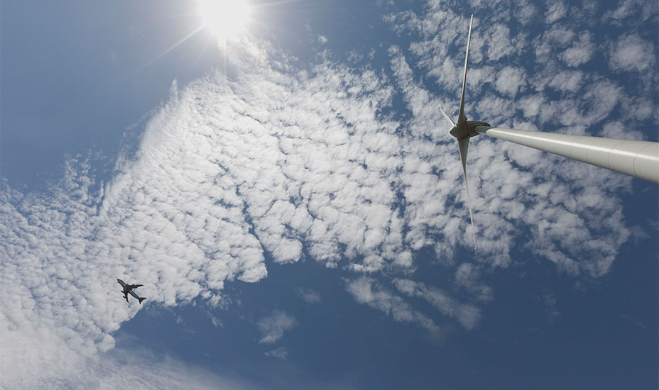 Een windmolen en een vliegtuig in de lucht